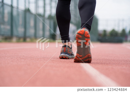 Closeup of a skilled runner legs in activewear, sprinting along the red rubberized track at an outdoor stadium. Closeup of a skilled runner legs in activewear, sprinting along the red rubberized track at an outdoor stadium. 123424884