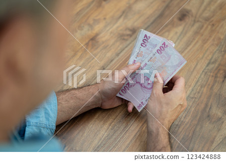 Male company accountant holds Turkish lira banknotes in hands preparing currency with high inflation for exchange procedure sitting at workplace in office 123424888