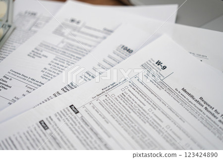 Request for Taxpayer Identification Number and Certification form placed on set of tax forms necessary for taxpayers to ensure accurate reporting of income 123424890