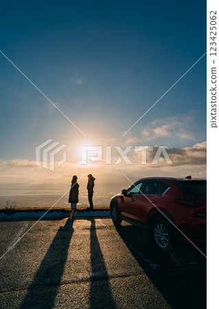 一對夫婦和一輛汽車在觀景台上觀看日落的剪影 123425062