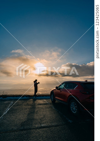 從觀景台觀看日落的一名男子和一輛汽車的輪廓 123425065