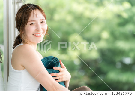 A woman taking a forest bath with a yoga mat in a forest or park (yoga, pilates, health care, refreshment) 123425779