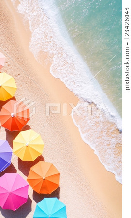 Aerial view captures the vibrant scene of colorful beach umbrellas arranged along the sandy shore, with gentle ocean waves lapping at the edge, creating a perfect summer holiday atmosphere 123426043