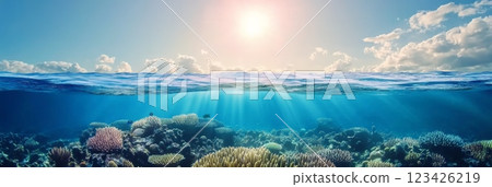 Sunlight beams through the rippling ocean surface, illuminating vibrant coral reefs below. Raindrops create a textured pattern on the water, enhancing the underwater scene's tranquility 123426219