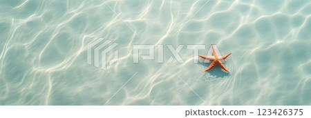 Orange starfish is gently floating on a rippling turquoise water surface, creating concentric circles, illuminated by sunlight, evoking tranquility and the beauty of marine life 123426375
