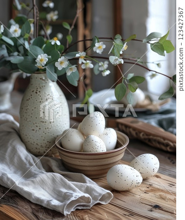 Decorative ceramic vase with flowers and speckled eggs on rustic wooden table 123427367