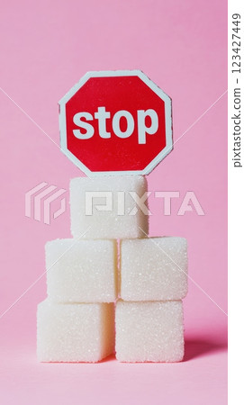 Four sugar cubes stacked together with a stop sign on top, conveying a message about reducing sugar consumption and promoting a healthy lifestyle 123427449