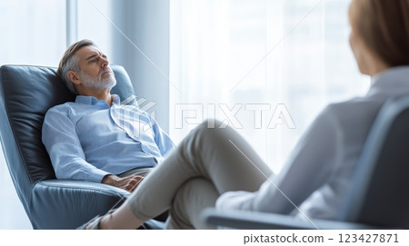 Mature man in a bright office, comfortably talking to his psychotherapist, creating a safe space for discussing mental health and well being Mature man in a bright office, comfortably talking to his psychotherapist, creating a safe space for discussing mental health and well being 123427871