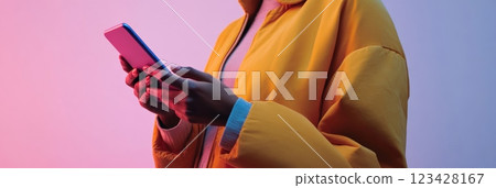 Close up of a young woman's hands holding and using a smartphone, illuminated by vibrant neon lights, creating a modern and stylish atmosphere focused on technology and communication Close up of a young woman's hands holding and using a smartphone, illuminated by vibrant neon lights, creating a modern and stylish atmosphere focused on technology and communication 123428167
