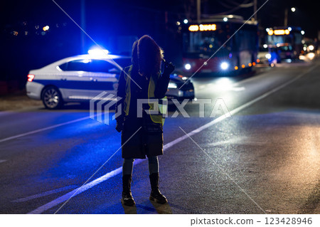 Protester with police cars in the background at night Protester with police cars in the background at night 123428946