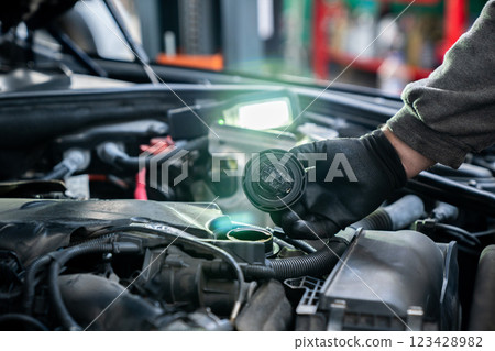 Serviceman checks the oil level in a car engine 123428982