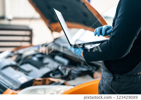 Serviceman with laptop checks car software in car service 123429089