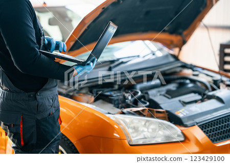 Serviceman with laptop checks car software in car service 123429100