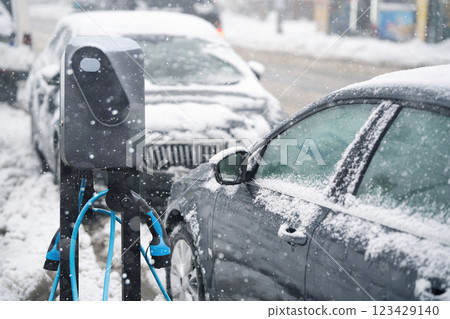 Electric car charging station on a background of snow covered winter cars. Electric car charging station on a background of snow covered winter cars. 123429140