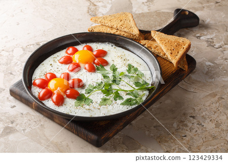 Children's food idea in the form of a flower of fried eggs, cherry tomatoes and parsley close-up in a plate. Horizontal 123429334