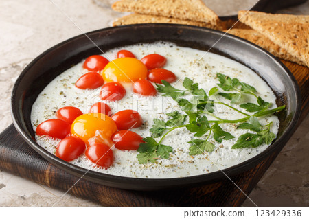 Flower shaped breakfast idea cooked fried eggs, parsley and cherry tomatoes close-up in a plate. Horizontal 123429336