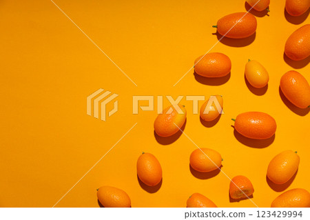 Kumquat on orange background, space for text 123429994