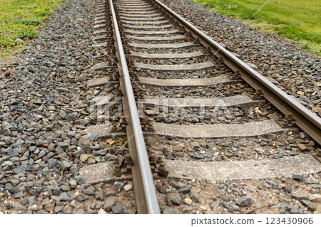 Single, diagonal railroad track through countryside landscape with a grass field. Empty railway track. Travel, adventure concept Single, diagonal railroad track through countryside landscape with a grass field. Empty railway track. Travel, adventure concept 123430906