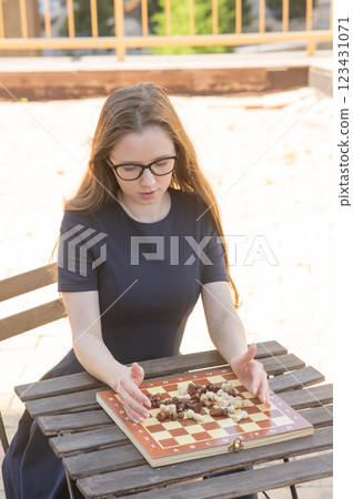 Caucasian woman playing chess outdoors. Caucasian woman playing chess outdoors. 123431071