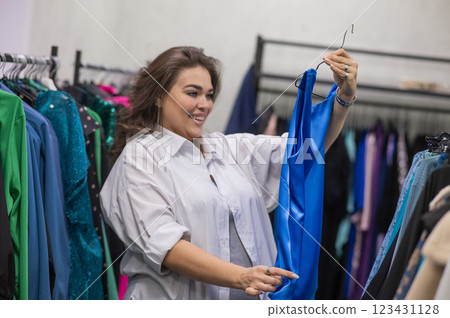 A fat woman chooses clothes in a plus size store.  123431128