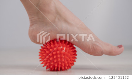 Close-up of a woman's foot on a massage ball with spikes.  123431132