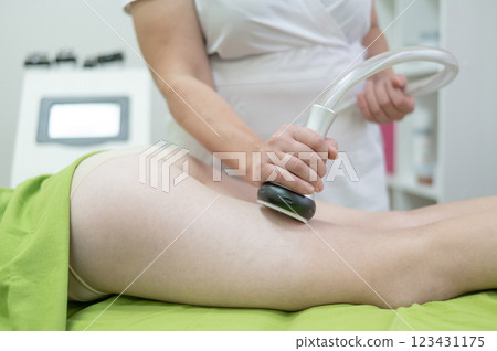 Caucasian woman on hardware anti-cellulite massage. Thigh cavitation procedure. Caucasian woman on hardware anti-cellulite massage. Thigh cavitation procedure. 123431175