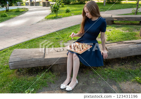 Caucasian woman playing chess outdoors. Caucasian woman playing chess outdoors. 123431196