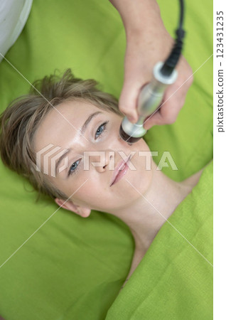 Top view of Caucasian woman undergoing radio wave RF lifting procedure in beauty salon. Top view of Caucasian woman undergoing radio wave RF lifting procedure in beauty salon. 123431235