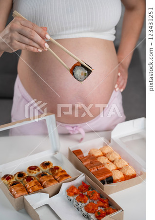 A pregnant woman stands at a table with rolls. Close-up of the belly. 123431251