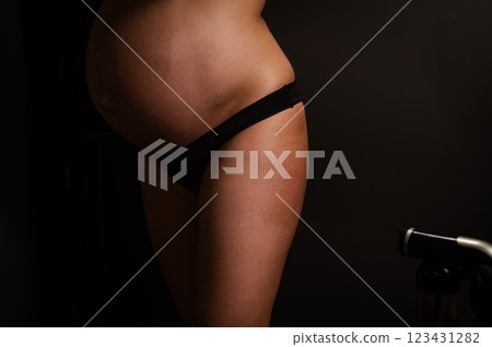 Faceless pregnant woman getting an instant tan. The master applies bronzer with a spray. 123431282