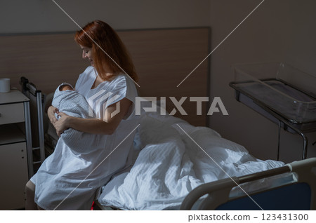 Caucasian woman holding newborn son while sitting on couch in maternity hospital ward.  123431300