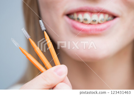 Close-up portrait of a woman with braces holding a floss to clean her teeth. Close-up portrait of a woman with braces holding a floss to clean her teeth. 123431463