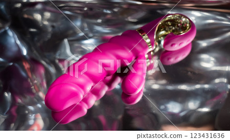 Sex toy on a metal background in the reflections of light.  123431636