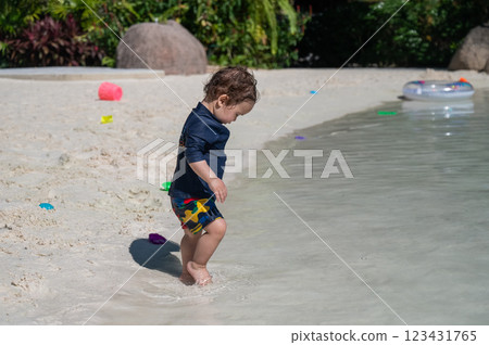 One year old Caucasian boy plays in the sand on the seashore.  123431765