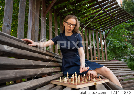 Caucasian woman playing chess outdoors. 123431820