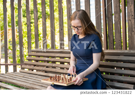 Caucasian woman playing chess outdoors. Caucasian woman playing chess outdoors. 123431822