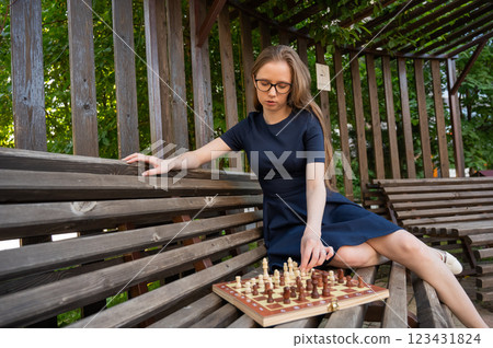 Caucasian woman playing chess outdoors. Caucasian woman playing chess outdoors. 123431824