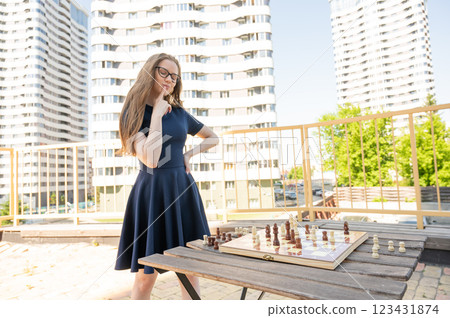 Caucasian woman playing chess outdoors. 123431874