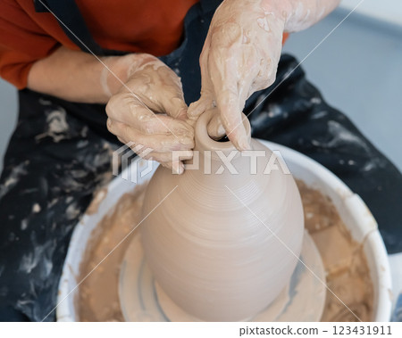 Close-up of a potter's hands making a ceramic vase on a potter's wheel. Close-up of a potter's hands making a ceramic vase on a potter's wheel. 123431911