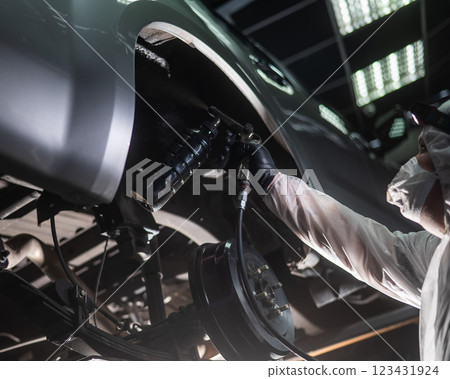 The master sprays an anti-corrosion compound on the bottom of the car. The master sprays an anti-corrosion compound on the bottom of the car. 123431924
