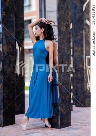 Beautiful asian ballerina in blue dress and pointe shoes posing outdoors. Vertical photo. Beautiful asian ballerina in blue dress and pointe shoes posing outdoors. Vertical photo. 123431952