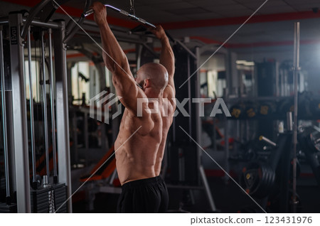 Caucasian man doing lat pull-downs on a machine. Caucasian man doing lat pull-downs on a machine. 123431976
