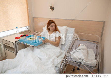 Caucasian woman eats on hospital bed after giving birth. Caucasian woman eats on hospital bed after giving birth. 123431986