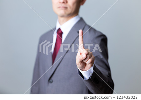 A middle-aged male businessman wearing a gray suit and pointing his index finger A middle-aged male businessman wearing a gray suit and pointing his index finger 123432022