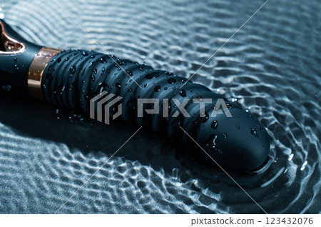 Black silicone vibrator in water. Circles on water around sex toy. Black silicone vibrator in water. Circles on water around sex toy. 123432076