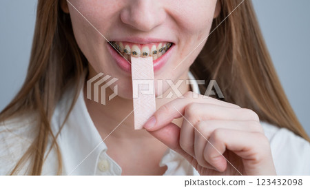 Young woman with metal braces on her teeth is chewing gum. Young woman with metal braces on her teeth is chewing gum. 123432098