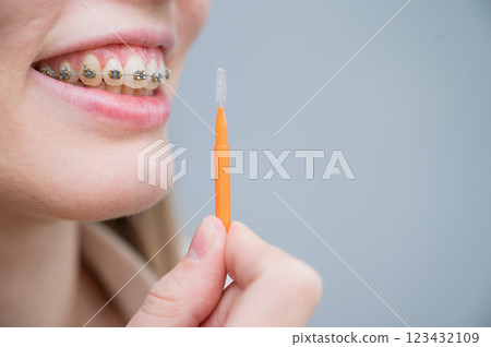 Unrecognizable Caucasian woman cleans braces with a brush. Close-up of female teeth with brackets 123432109