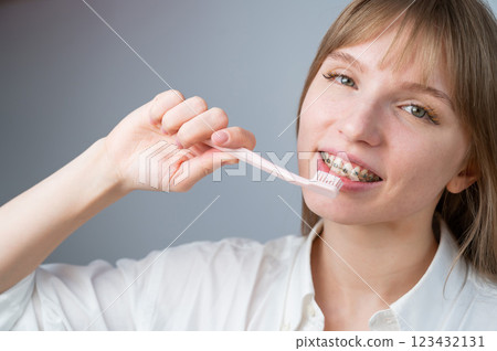 Portrait of a caucasian woman with braces on her teeth holding a toothbrush. 123432131