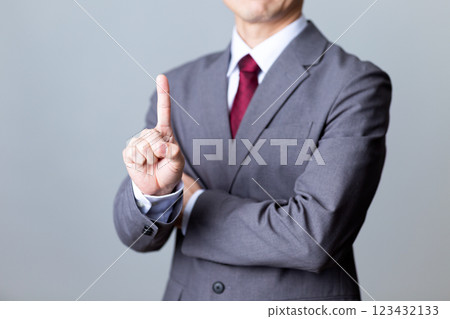A middle-aged male businessman wearing a gray suit and pointing his index finger 123432133