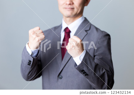 A middle-aged male businessman wearing a gray suit and making a fist pump A middle-aged male businessman wearing a gray suit and making a fist pump 123432134